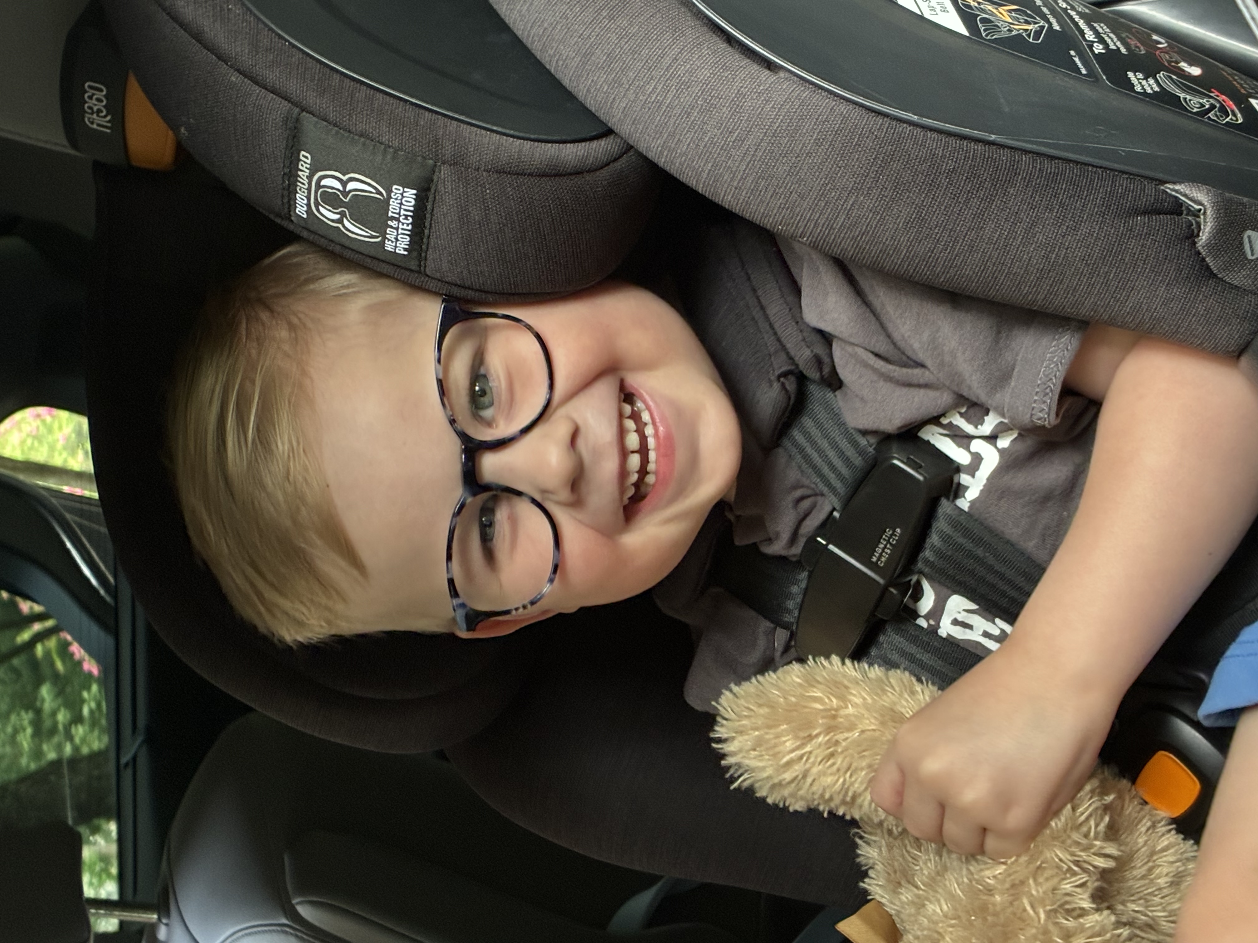 Felix, a joyful four-year-old boy in glasses, grinning as he hugs his teddy bear
