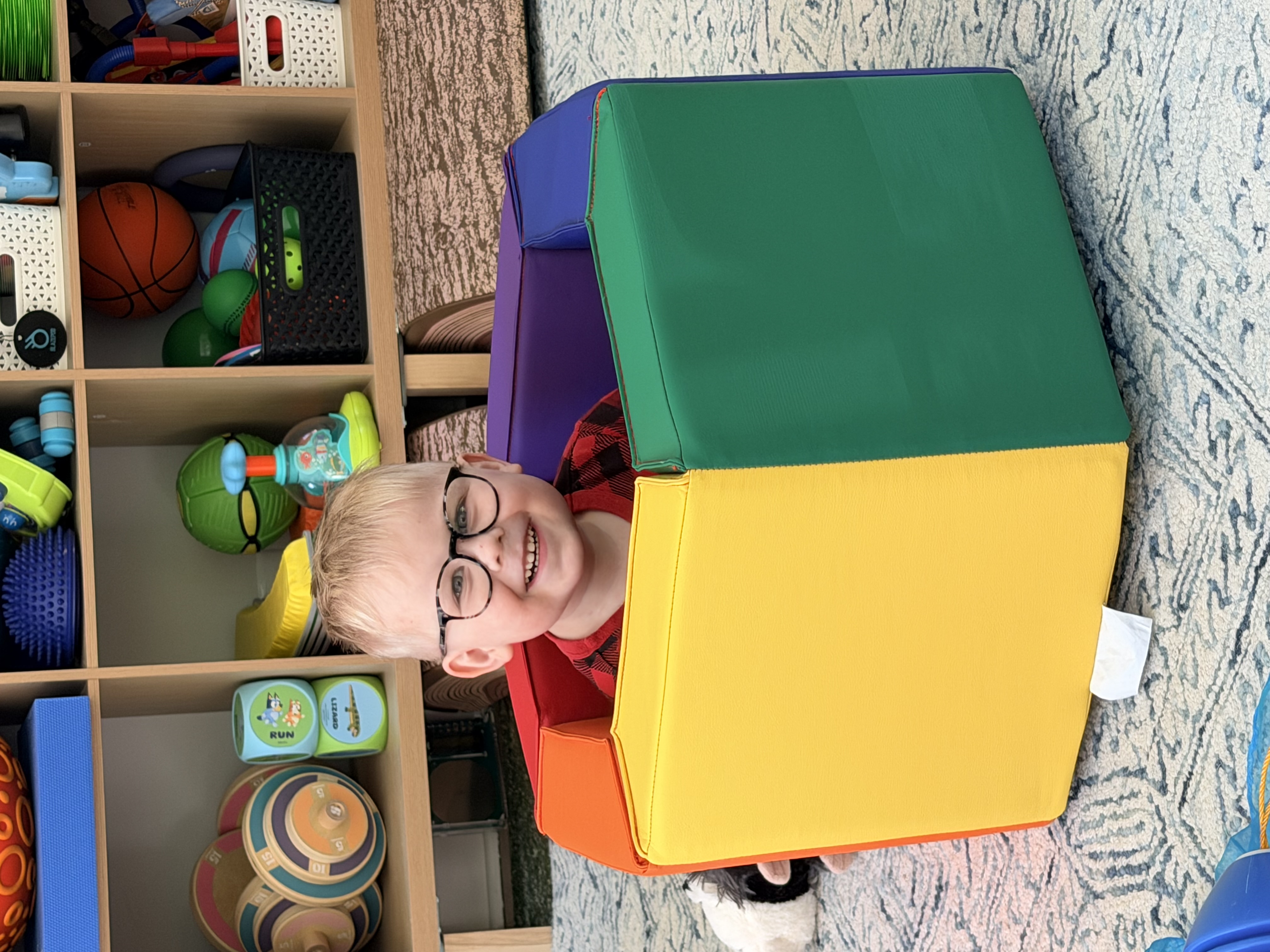 Felix beaming from inside a colorful play chair